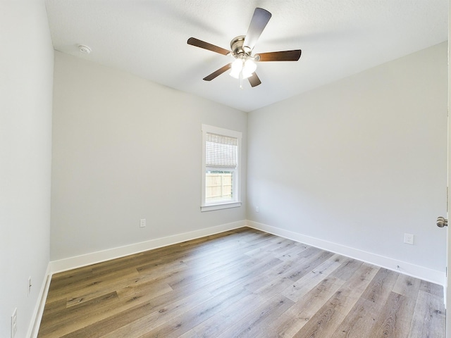 spare room with ceiling fan, light wood finished floors, and baseboards