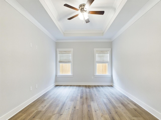 unfurnished room with light wood-type flooring, a raised ceiling, a healthy amount of sunlight, and baseboards