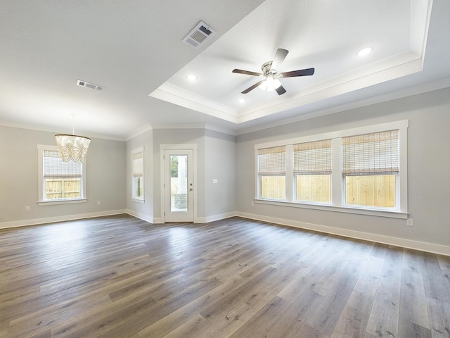 unfurnished room featuring dark wood-style floors, visible vents, a tray ceiling, and crown molding