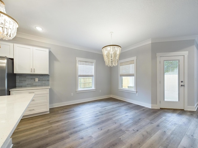 unfurnished dining area with baseboards, dark wood finished floors, a wealth of natural light, and an inviting chandelier