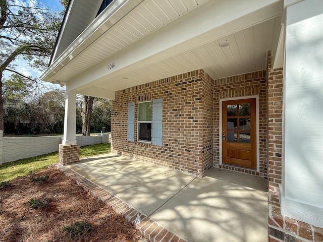 property entrance featuring covered porch and brick siding