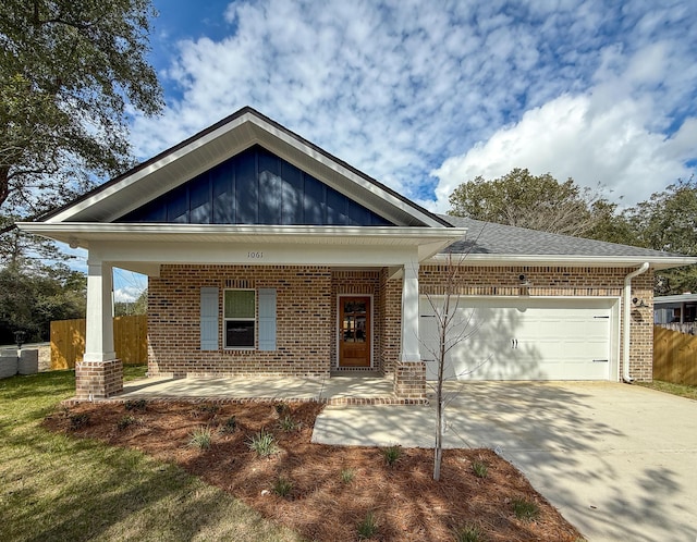 craftsman house featuring brick siding, a porch, concrete driveway, an attached garage, and fence