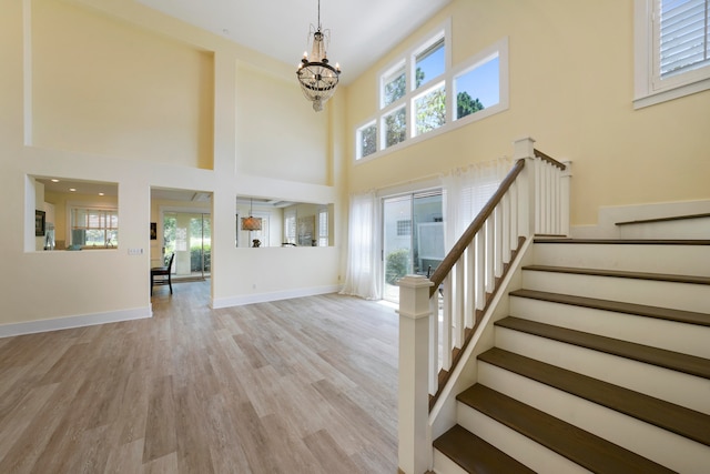 entrance foyer featuring a towering ceiling, light wood-type flooring, and an inviting chandelier