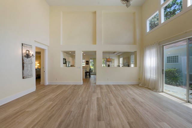 unfurnished living room with a high ceiling and light hardwood / wood-style flooring