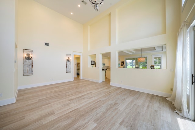 unfurnished living room featuring a towering ceiling and light wood-type flooring