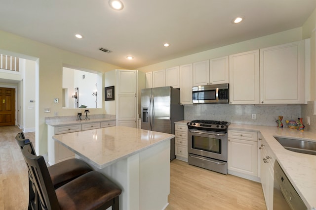 kitchen with light wood-type flooring, stainless steel appliances, a breakfast bar area, and a center island