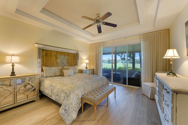 bedroom featuring access to exterior, light hardwood / wood-style flooring, ceiling fan, and a raised ceiling