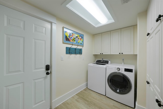 clothes washing area with cabinets, independent washer and dryer, and light hardwood / wood-style flooring