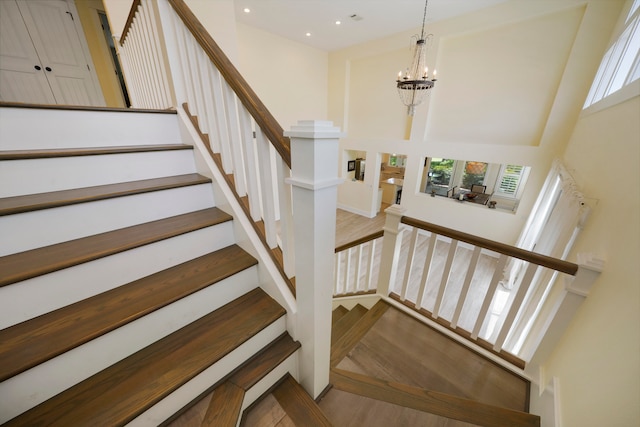 staircase featuring wood-type flooring and an inviting chandelier