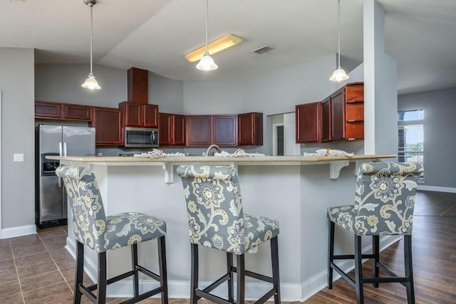 kitchen featuring appliances with stainless steel finishes, lofted ceiling, dark wood-type flooring, and a breakfast bar area