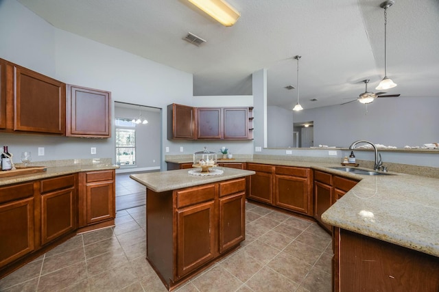 kitchen featuring lofted ceiling, ceiling fan with notable chandelier, sink, decorative light fixtures, and a kitchen island