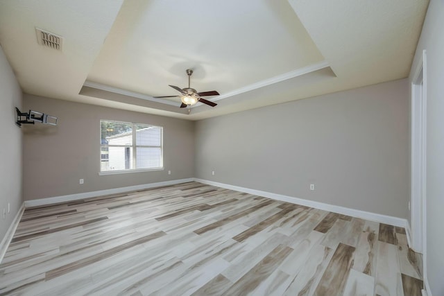 unfurnished room with light hardwood / wood-style flooring, a raised ceiling, and ceiling fan