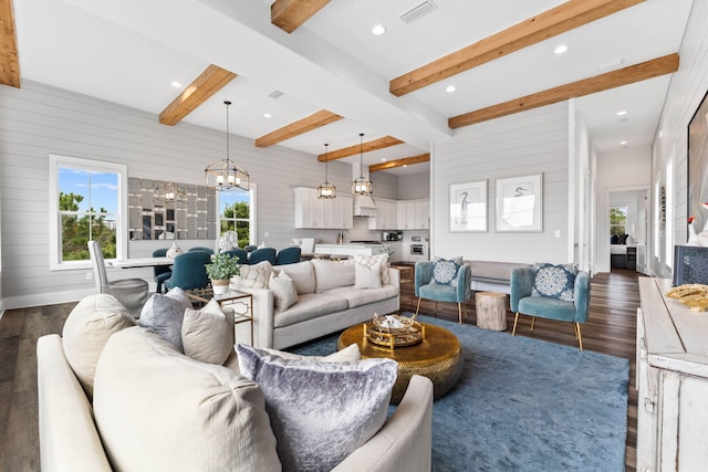 living room with beam ceiling, dark hardwood / wood-style floors, an inviting chandelier, and wood walls