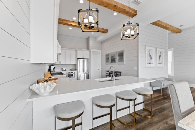 kitchen featuring white cabinetry, sink, pendant lighting, beam ceiling, and appliances with stainless steel finishes