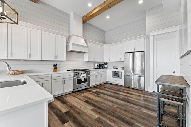 kitchen with beam ceiling, dark wood-type flooring, premium appliances, a towering ceiling, and white cabinets