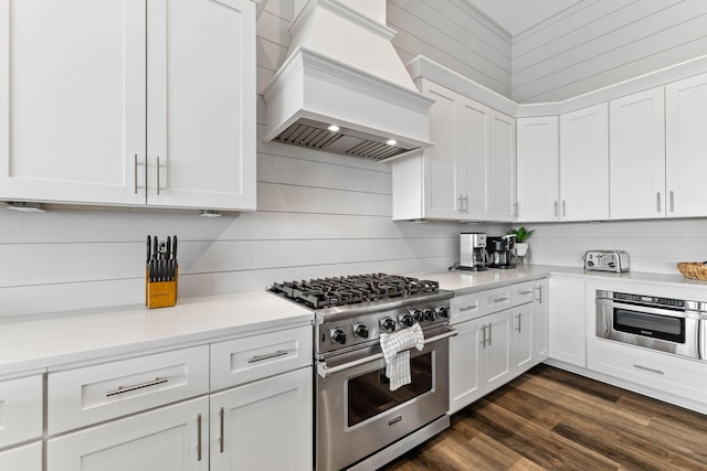 kitchen featuring dark hardwood / wood-style flooring, premium range hood, white cabinetry, and stainless steel appliances