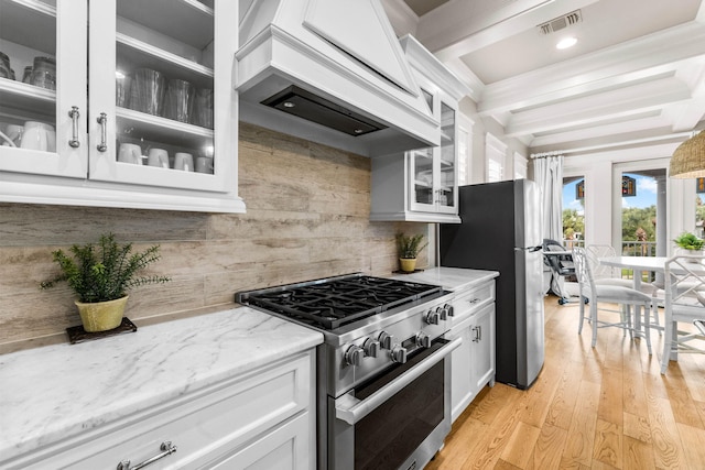 kitchen with light stone countertops, white cabinetry, beamed ceiling, light hardwood / wood-style floors, and appliances with stainless steel finishes