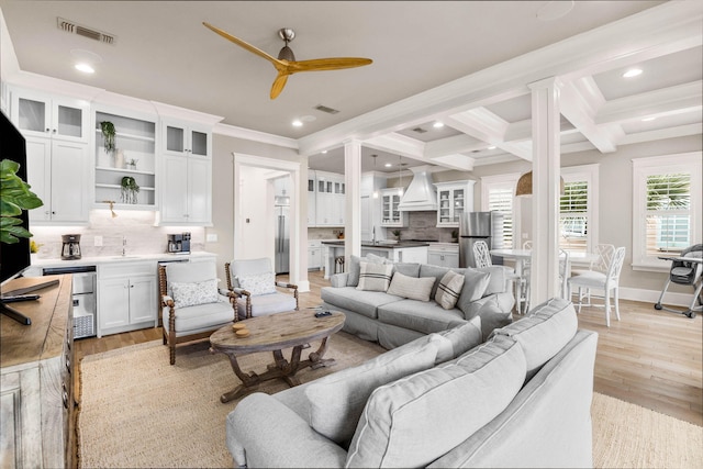 living room featuring ornamental molding, coffered ceiling, ceiling fan, beamed ceiling, and light hardwood / wood-style floors