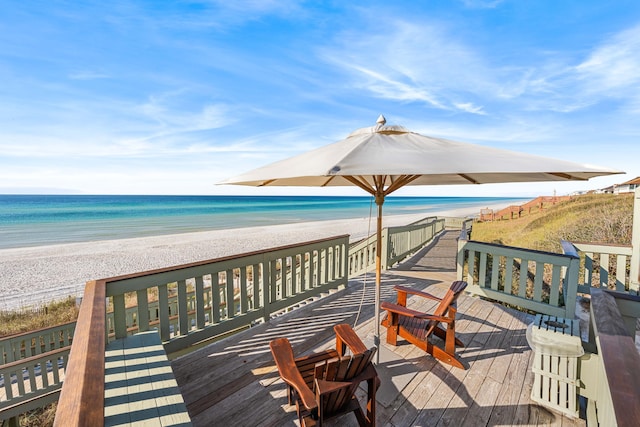 wooden deck featuring a beach view and a water view