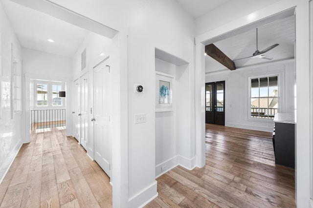 hallway featuring beam ceiling and light hardwood / wood-style floors