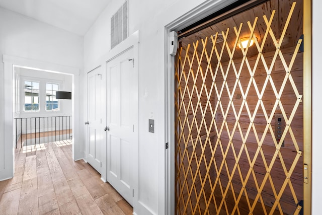 corridor featuring elevator and light wood-type flooring