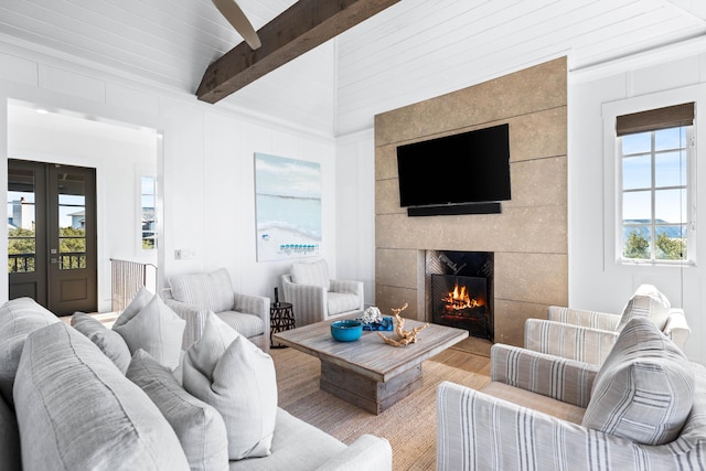 living room with beam ceiling, a fireplace, plenty of natural light, and light hardwood / wood-style flooring