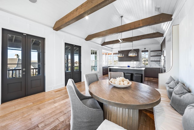 dining room with lofted ceiling with beams and light hardwood / wood-style flooring