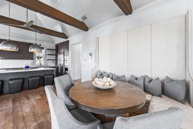 dining space with vaulted ceiling with beams and light hardwood / wood-style flooring