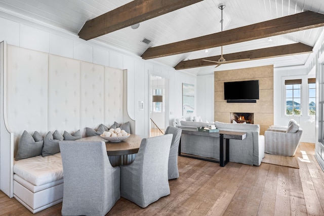 dining area featuring vaulted ceiling with beams, ceiling fan, hardwood / wood-style floors, and a fireplace