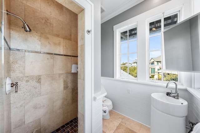 bathroom featuring tile patterned flooring, a tile shower, tile walls, and ornamental molding