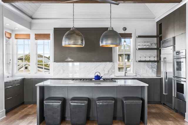 kitchen with a center island, dark wood-type flooring, hanging light fixtures, and stainless steel appliances