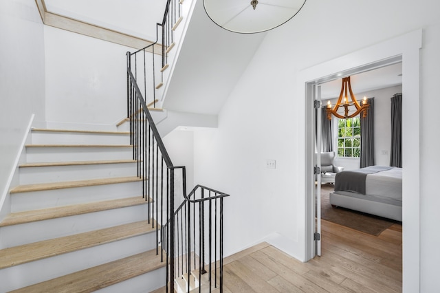 stairs featuring hardwood / wood-style flooring and a chandelier