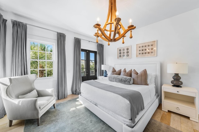 bedroom featuring french doors, light hardwood / wood-style floors, and an inviting chandelier