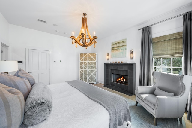 bedroom with a chandelier and a tiled fireplace