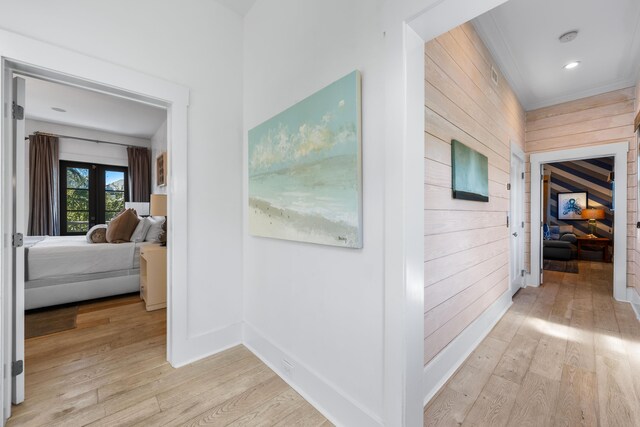 hall with wood walls, light wood-type flooring, and french doors