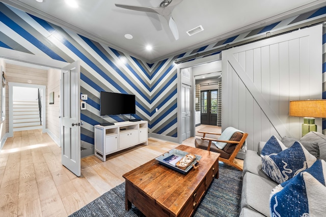 living room featuring ceiling fan, ornamental molding, and light hardwood / wood-style flooring