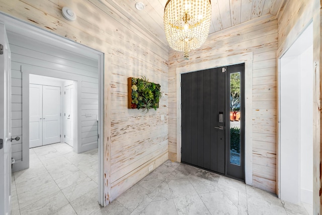 entryway with wooden walls, wooden ceiling, and an inviting chandelier