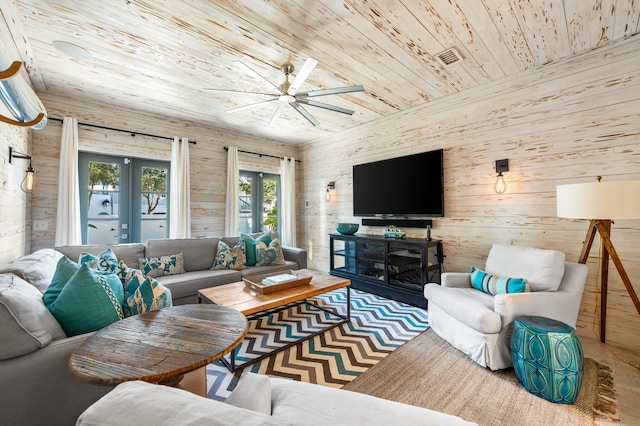 living room featuring ceiling fan, wood walls, wooden ceiling, and french doors