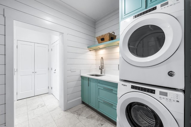 laundry room with stacked washer / drying machine, cabinets, sink, and crown molding