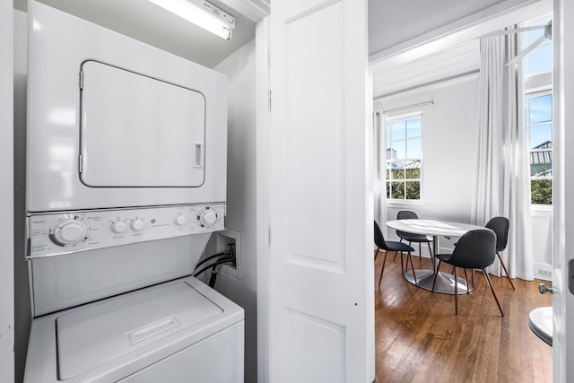 washroom with wood-type flooring and stacked washer / dryer