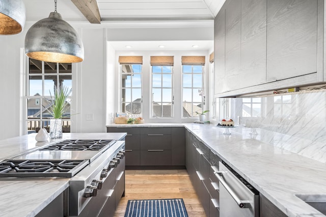 kitchen with beam ceiling, decorative light fixtures, light stone counters, and light hardwood / wood-style floors