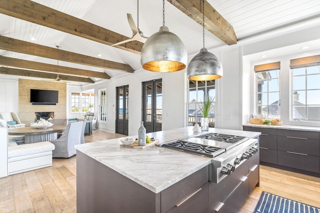 kitchen featuring pendant lighting, light hardwood / wood-style flooring, stainless steel gas stovetop, a large island, and a tiled fireplace