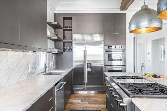 kitchen with light stone countertops, sink, dark hardwood / wood-style flooring, decorative light fixtures, and appliances with stainless steel finishes