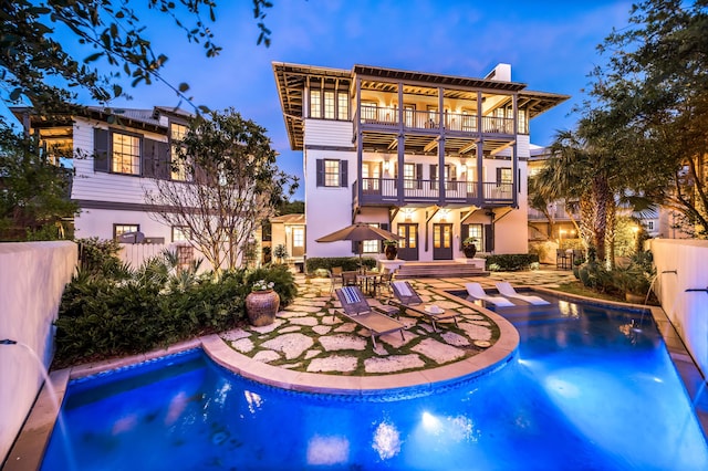 rear view of house with a patio, a balcony, and a fenced in pool