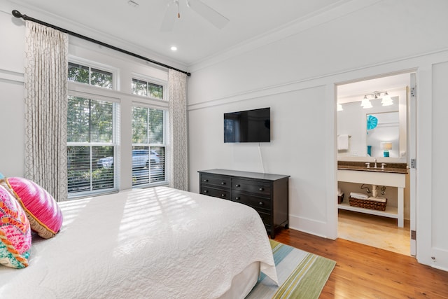 bedroom featuring ensuite bathroom, sink, ceiling fan, light wood-type flooring, and ornamental molding