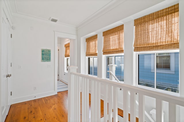 hallway with light wood-type flooring and crown molding