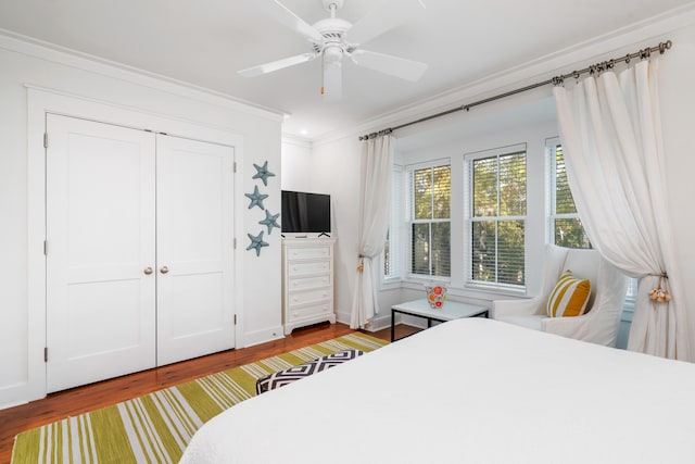 bedroom with a closet, hardwood / wood-style flooring, ceiling fan, and ornamental molding