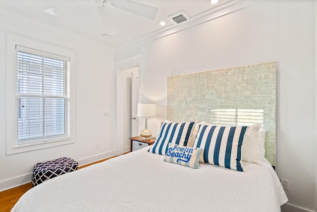 bedroom with hardwood / wood-style flooring, ceiling fan, and ornamental molding