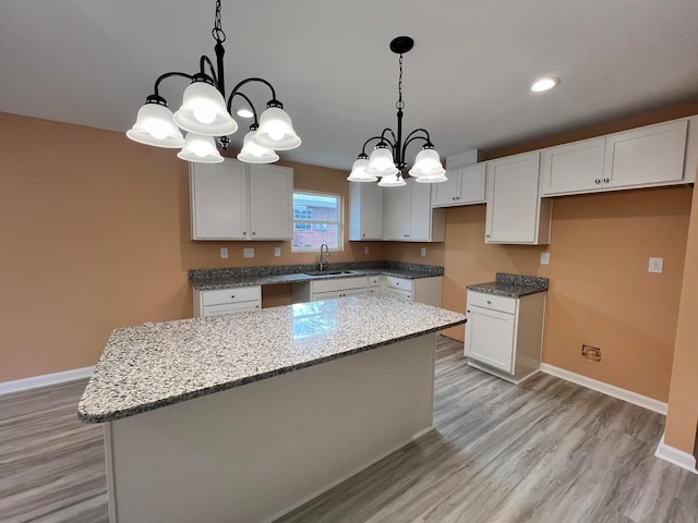 kitchen with light wood-type flooring, white cabinetry, pendant lighting, and a center island