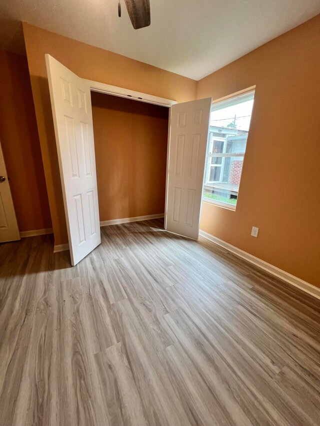 unfurnished bedroom featuring light hardwood / wood-style floors, ceiling fan, and a closet
